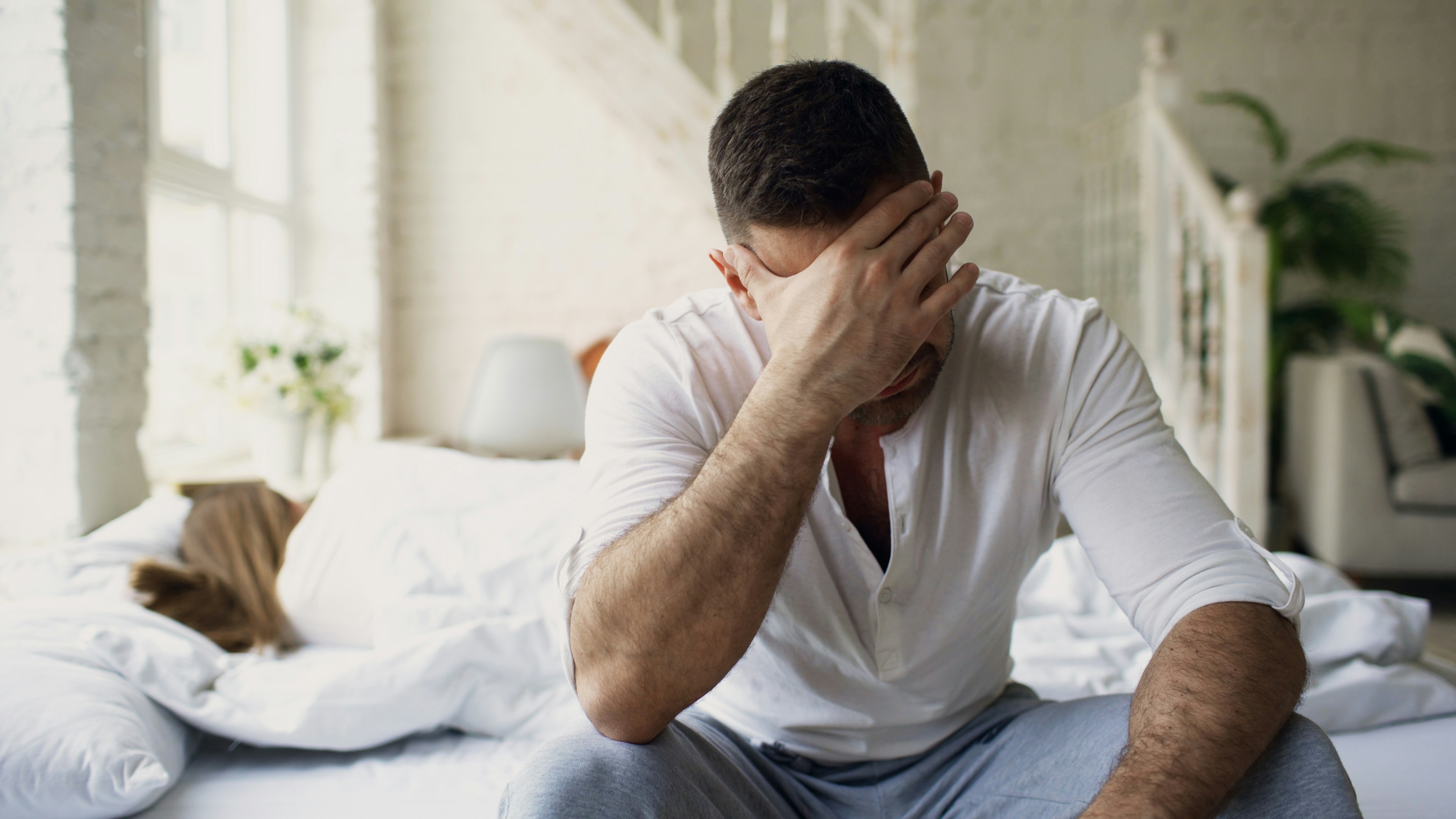 Man distressed on the side of bed